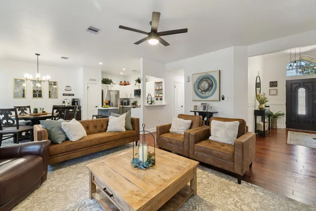 a living room with furniture kitchen view and a chandelier