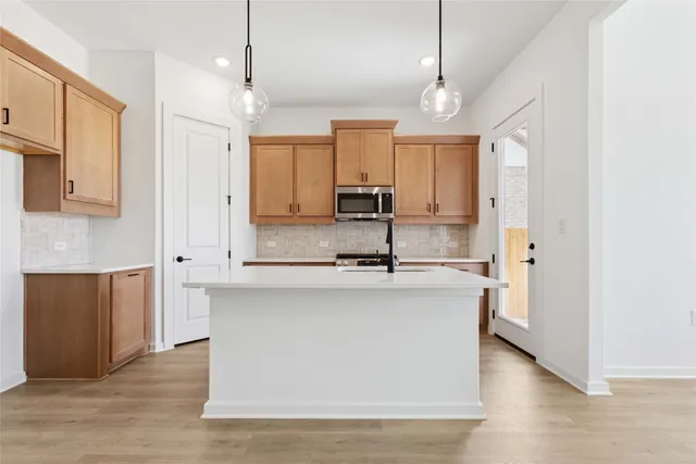 a large kitchen with stainless steel appliances granite countertop a sink a stove and a refrigerator