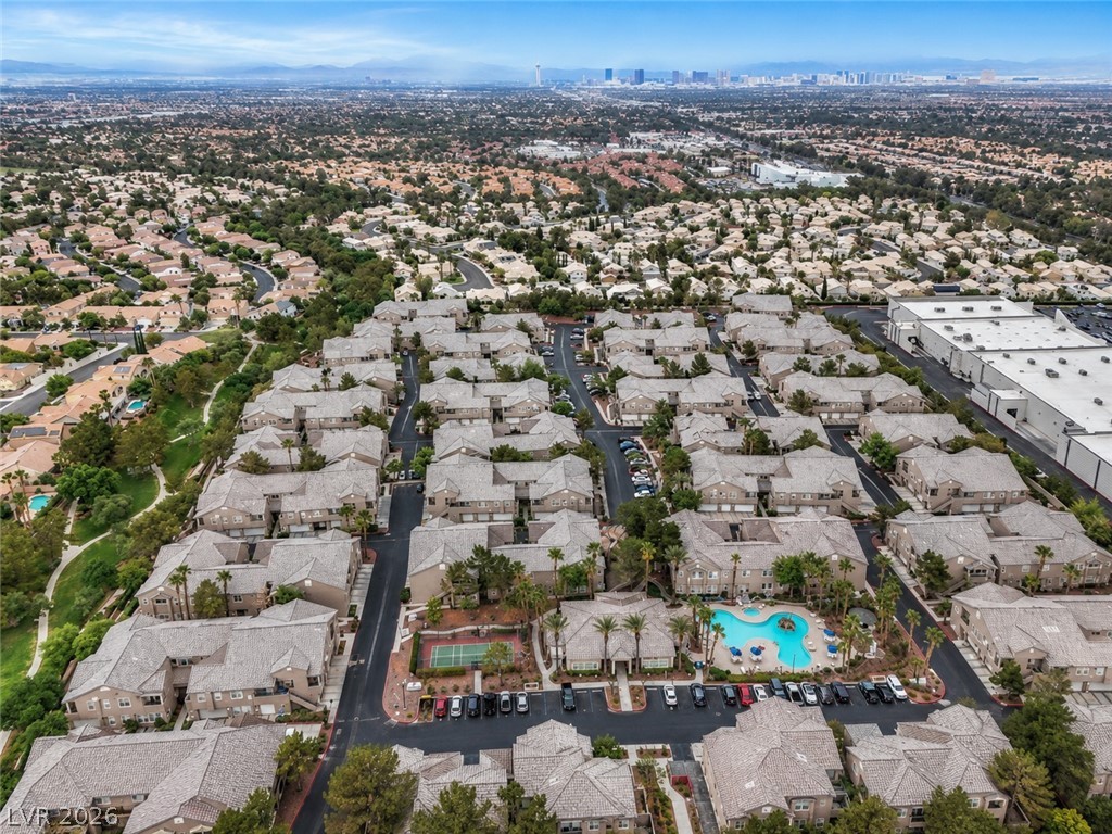 2153 Quarry Ridge Street, Unit 103 Las Vegas, NV 89117 - Photo 35 of 42 An aerial panorama reveals a vast community with diverse housing, green spaces, and a city skyline beyond.