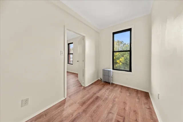 a view of empty room with window and wooden floor