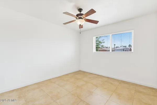 an empty room with ceiling fan and window