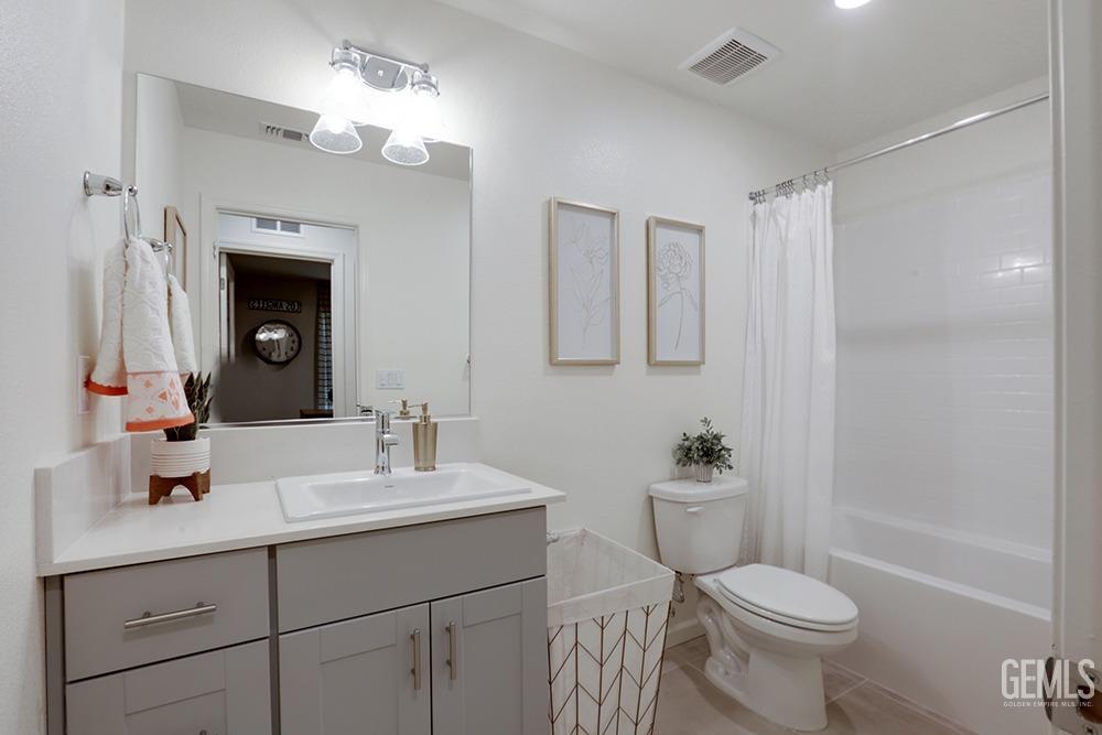 Undisclosed Address Bakersfield, CA 93313 - Photo 23 of 30 a bathroom with a sink a toilet a mirror a vanity and shower