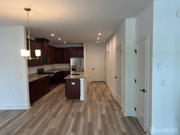 a kitchen with stainless steel appliances granite countertop a refrigerator a sink dishwasher a stove and white countertops with wooden floor