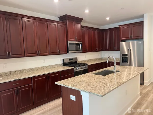 a kitchen with granite countertop stainless steel appliances wooden cabinets and a sink