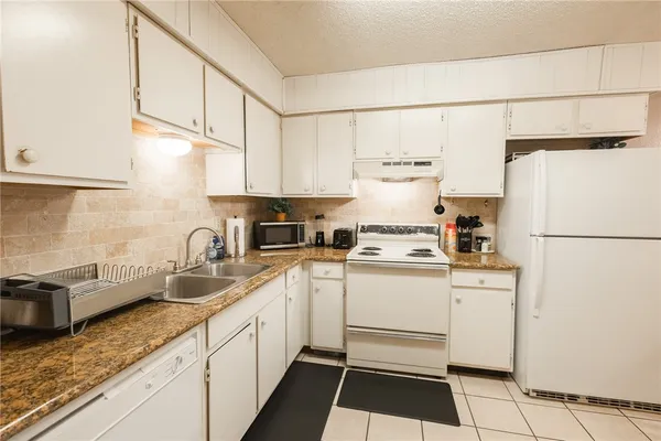a kitchen with a sink a refrigerator and cabinets