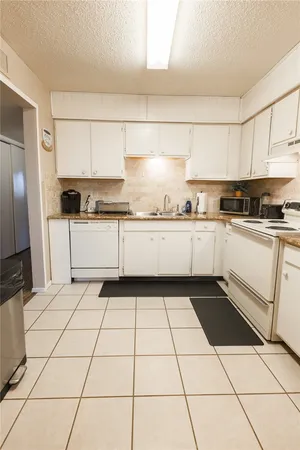 a kitchen with granite countertop a stove a sink and a refrigerator