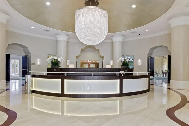 a living room with stainless steel appliances furniture a rug and a chandelier