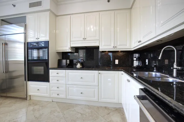 a kitchen with granite countertop white cabinets and stainless steel appliances
