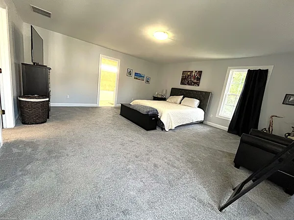 a bedroom with a bed flat screen tv and window