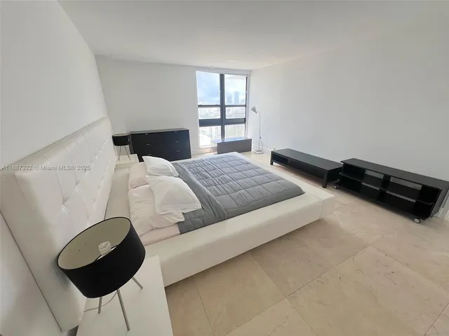 a bedroom with a bed a window and dresser