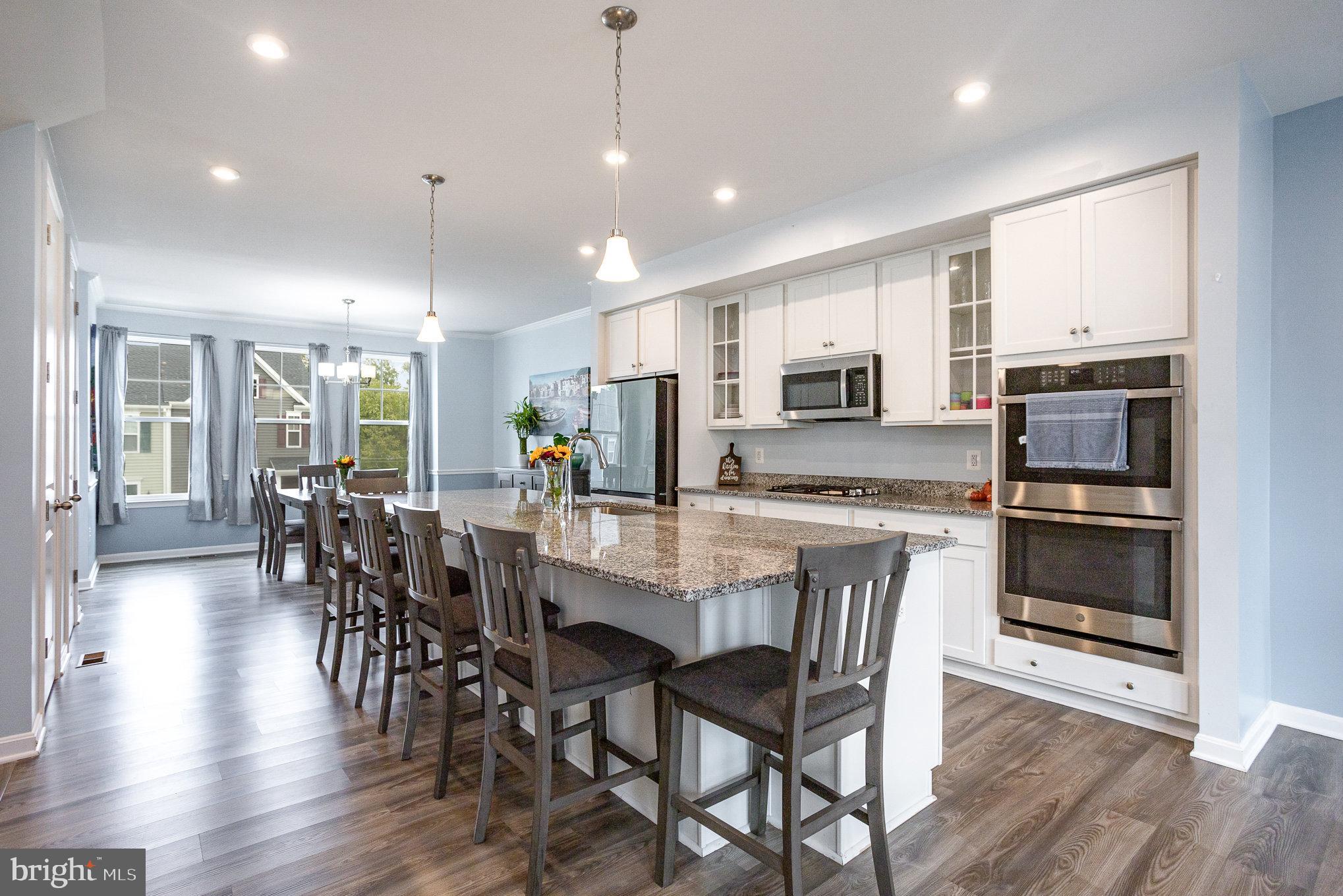 18236 Summit Pointe Drive Triangle, VA 22172 - Photo 14 of 36 a kitchen with stainless steel appliances a dining table chairs stove refrigerator and cabinets