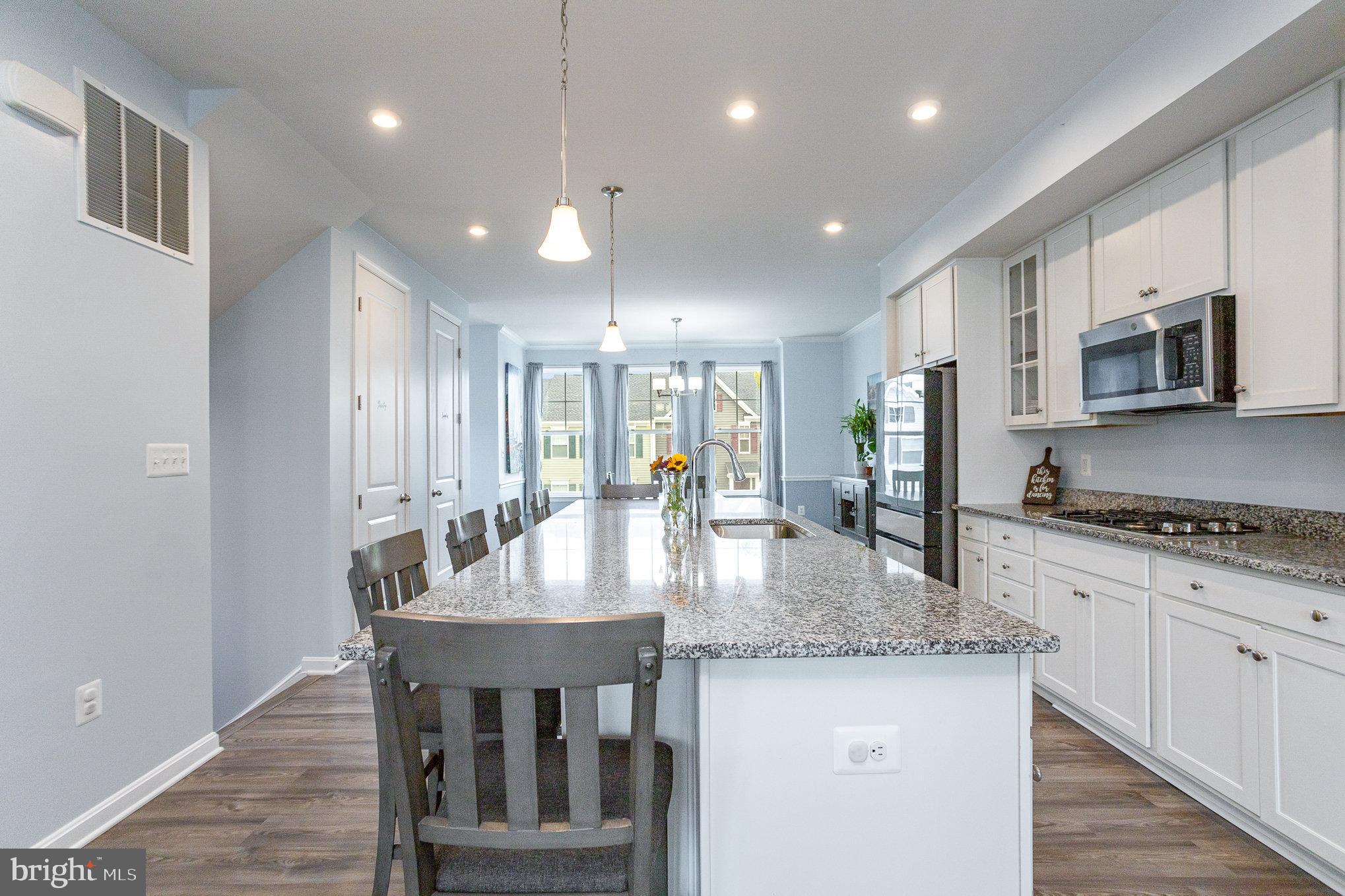 18236 Summit Pointe Drive Triangle, VA 22172 - Photo 15 of 36 a kitchen with stainless steel appliances granite countertop a stove a refrigerator a kitchen island a table and chairs