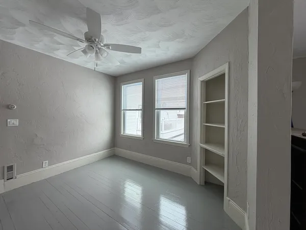 an empty room with windows and fan