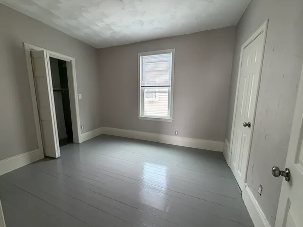 an empty room with window and hardwood floor