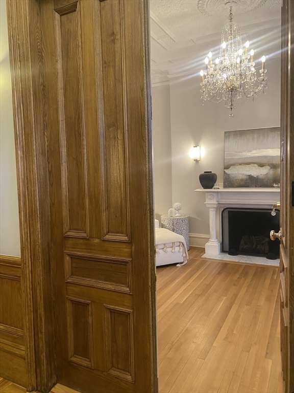 214 Commonwealth Avenue, Unit 1 Boston, MA 02116 - Photo 12 of 22 a view of a livingroom with wooden floor a fireplace and chandelier