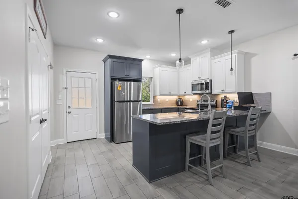 a kitchen with kitchen island granite countertop a sink cabinets and wooden floor