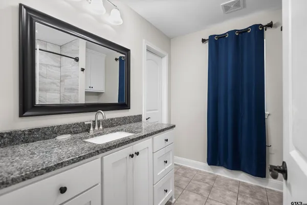 a bathroom with a granite countertop sink and a mirror