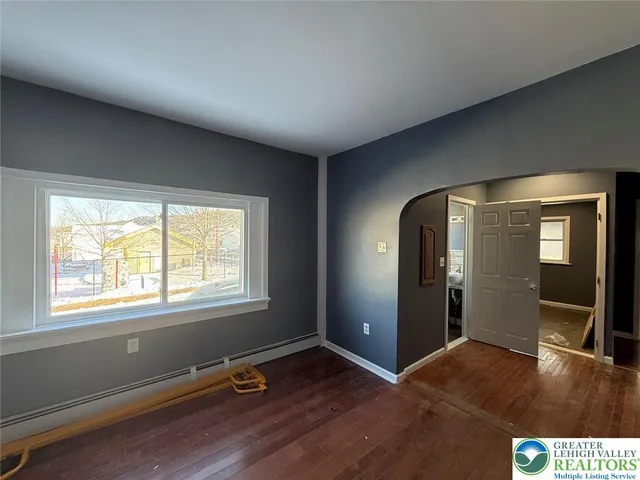 a view of an empty room with a window and wooden floor