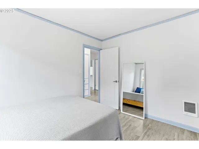 a view of a bedroom with a bed and wooden floor