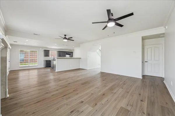 an empty room with wooden floor a ceiling fan and windows