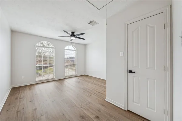 a view of a room with wooden floor ceiling fan and window