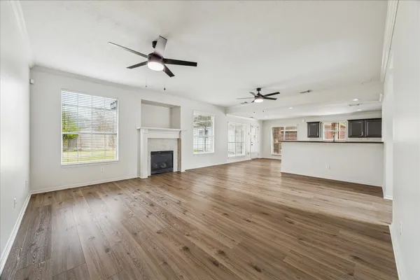 a view of a livingroom with wooden floor a ceiling fan and windows