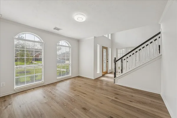 a view of an empty room with wooden floor and a window