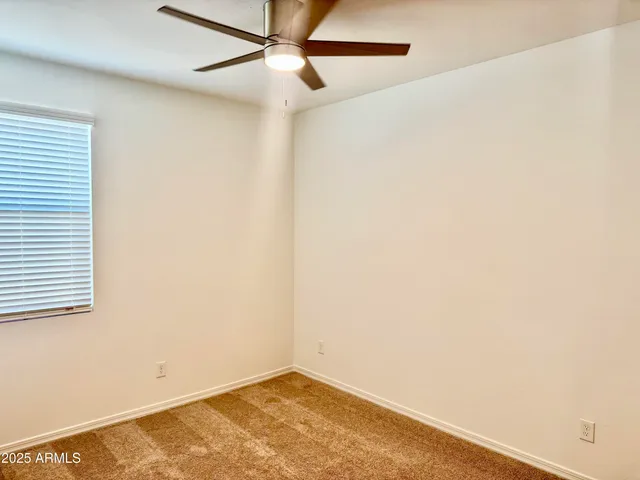 an empty room with a window and a fan