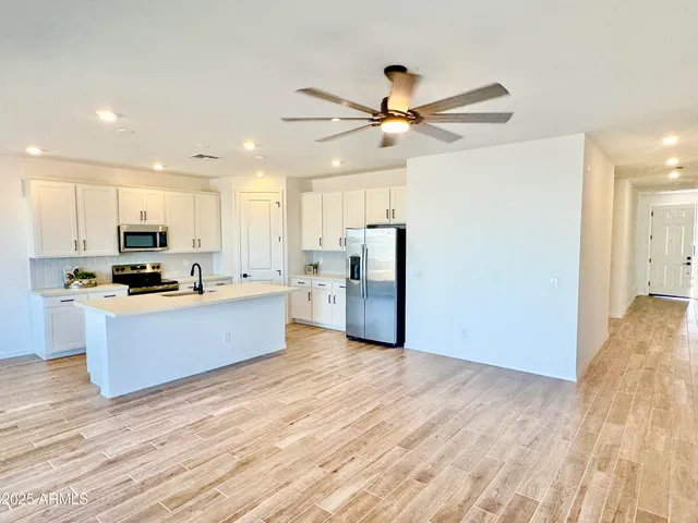 a large kitchen with stainless steel appliances granite countertop a stove a refrigerator a sink a center island and wooden floor