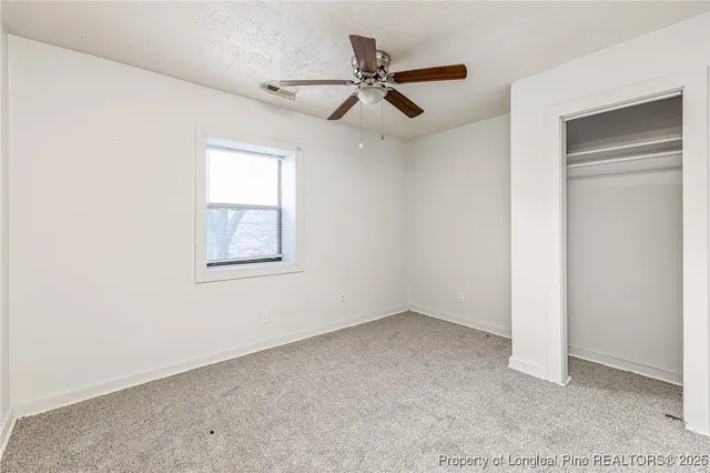 an empty room with a window and a fan
