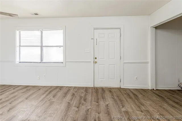 an empty room with a wooden floor and windows