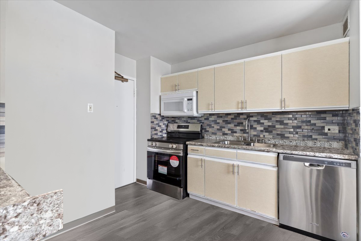 6171 North Sheridan Road, Unit 1112 Chicago, IL 60660 - Photo 7 of 23 a kitchen with granite countertop white cabinets and appliances