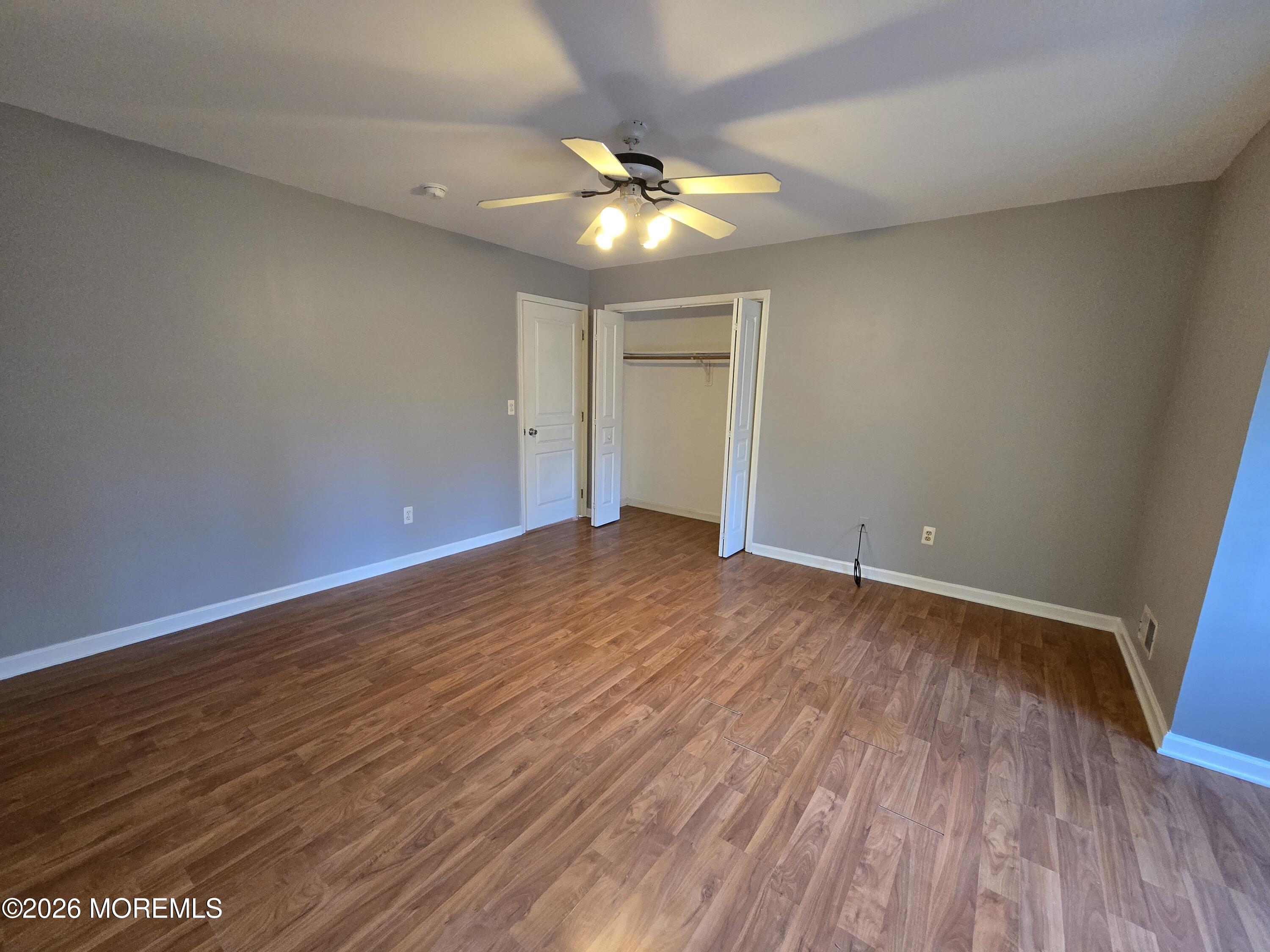 274 Easy Street, Unit RIGHT Howell, NJ 07731 - Photo 14 of 19 an empty room with wooden floor and a ceiling fan