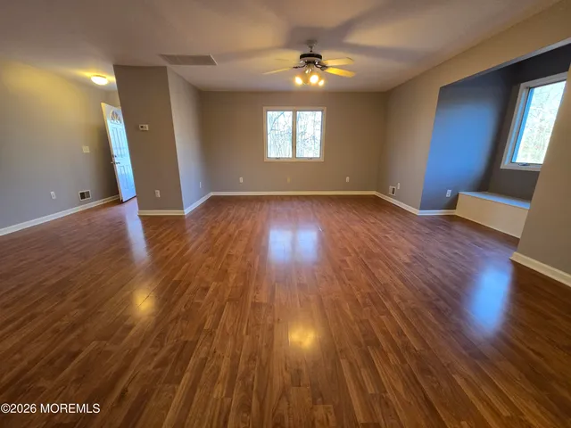 an empty room with wooden floor and windows