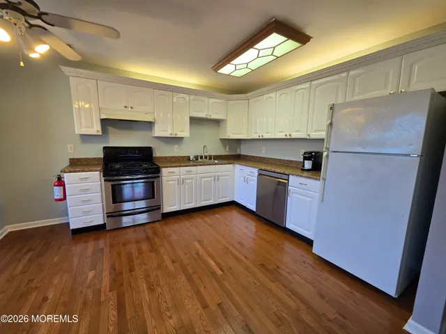 a kitchen with granite countertop wooden floors and stainless steel appliances