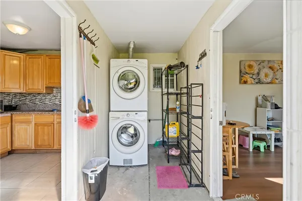 a utility room with fridge and wooden floor