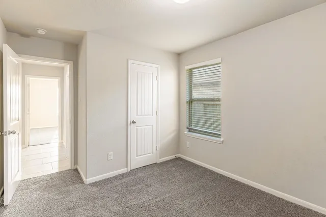 a view of an empty room with closet and a window