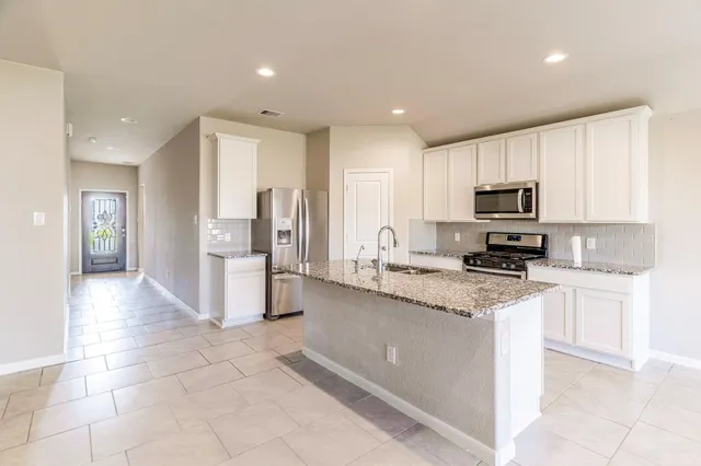 a kitchen with stainless steel appliances granite countertop a refrigerator and a stove top oven