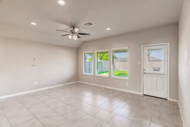 an empty room with windows and fan