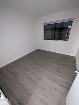 a view of an empty room with wooden floor and a fireplace