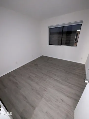 a view of an empty room with wooden floor and a fireplace