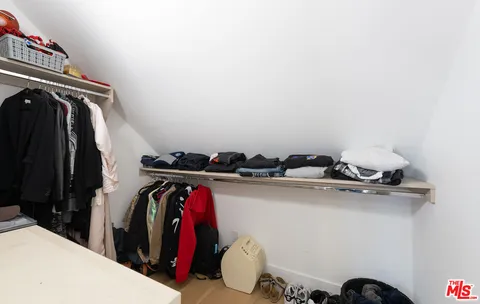 a view of walk in closet with clothes and shoes