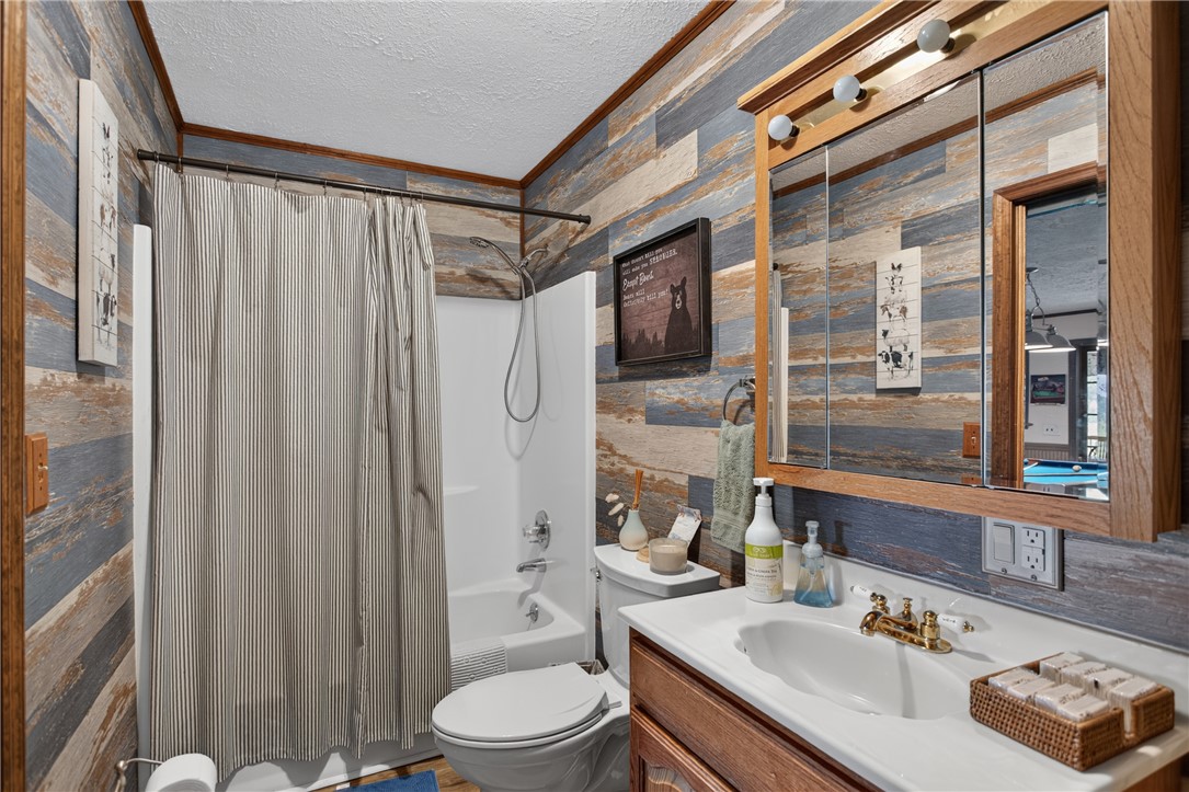 351 River Road Westminster, SC 29693 - Photo 18 of 50 A well-lit bathroom with a vanity and a combined shower-bathtub unit, featuring a multi-toned wood plank wall.