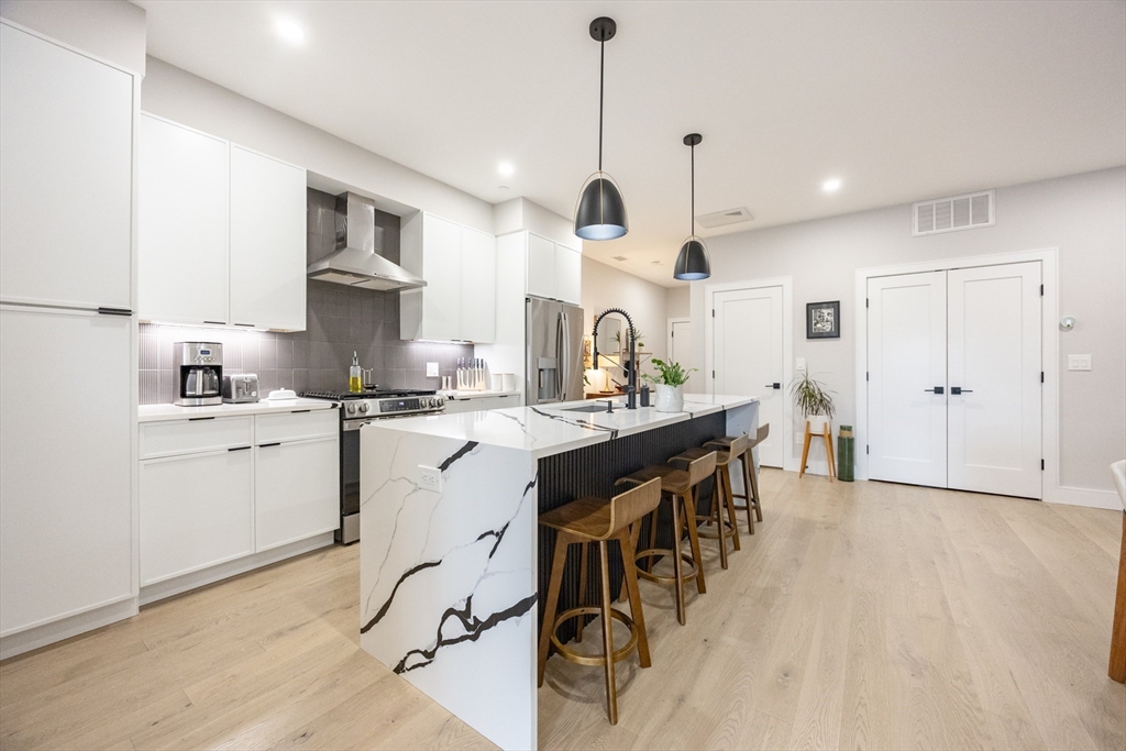 70 Shawsheen Road, Unit PH5 Boston, MA 02128 - Photo 2 of 42 a kitchen with kitchen island granite countertop a sink a center island a counter space and a window