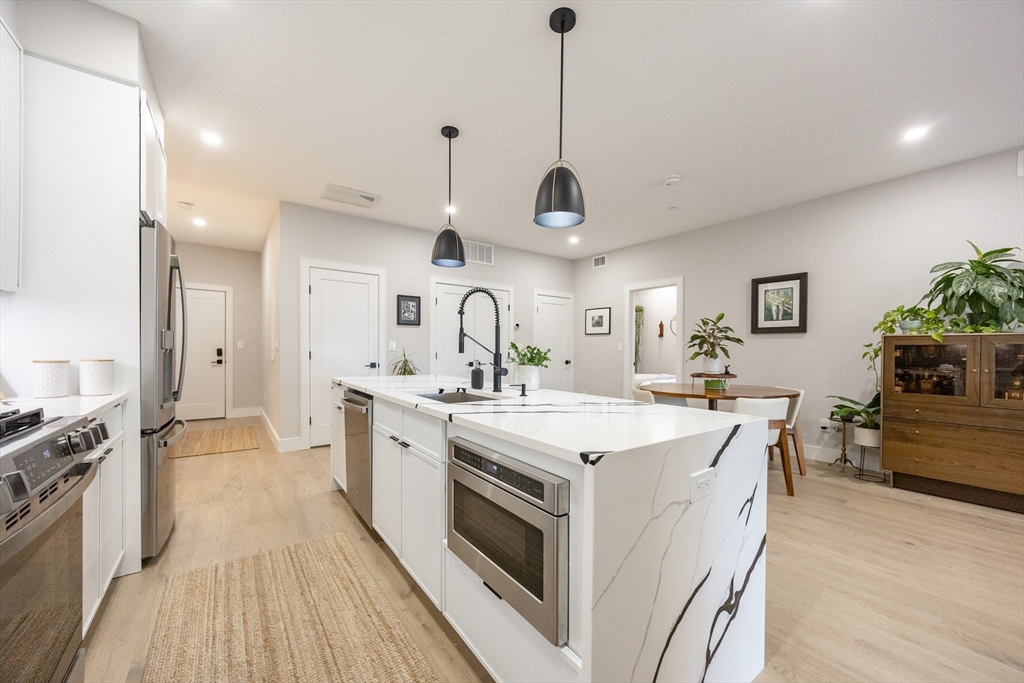 70 Shawsheen Road, Unit PH5 Boston, MA 02128 - Photo 7 of 42 a large kitchen with stainless steel appliances a stove a sink dishwasher and white cabinets with wooden floor