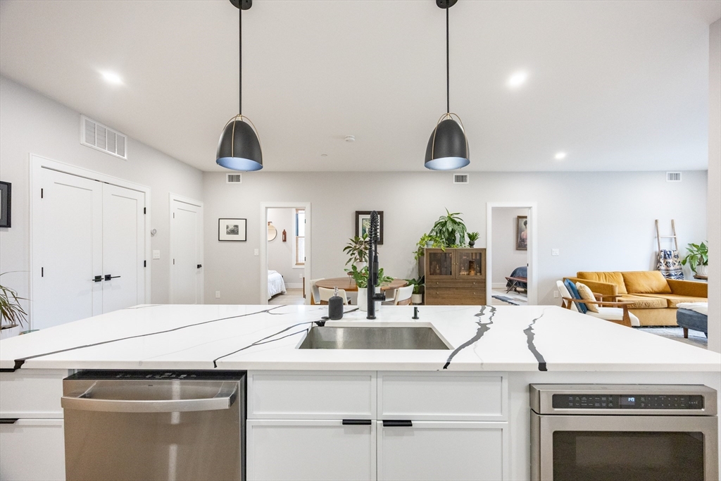 70 Shawsheen Road, Unit PH5 Boston, MA 02128 - Photo 8 of 42 a kitchen with stainless steel appliances granite countertop a sink a oven a dining table and chairs with wooden floor