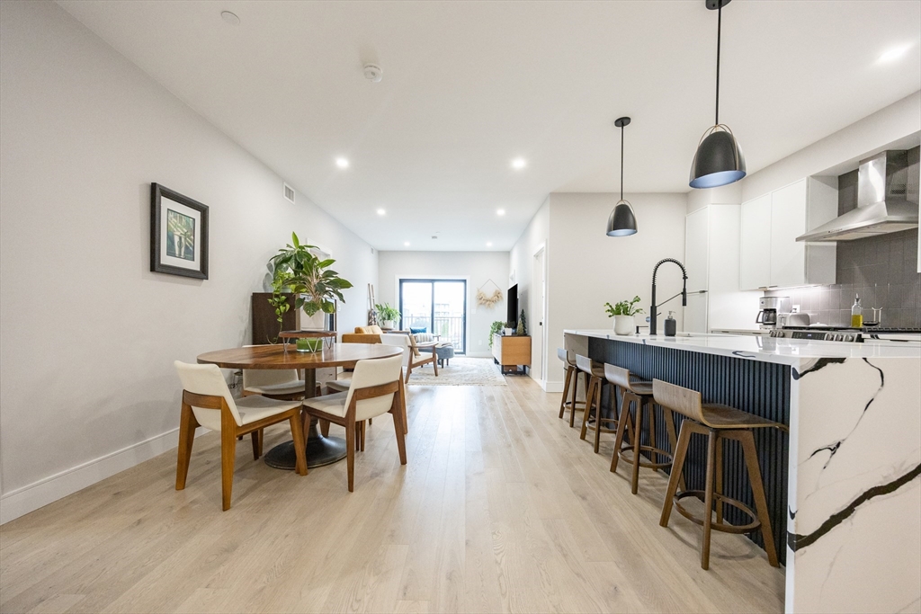 70 Shawsheen Road, Unit PH5 Boston, MA 02128 - Photo 9 of 42 a kitchen with stainless steel appliances a dining table chairs stove and wooden floor