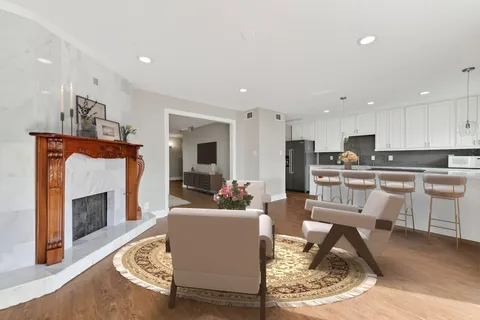 a living room with furniture a fireplace and a kitchen view