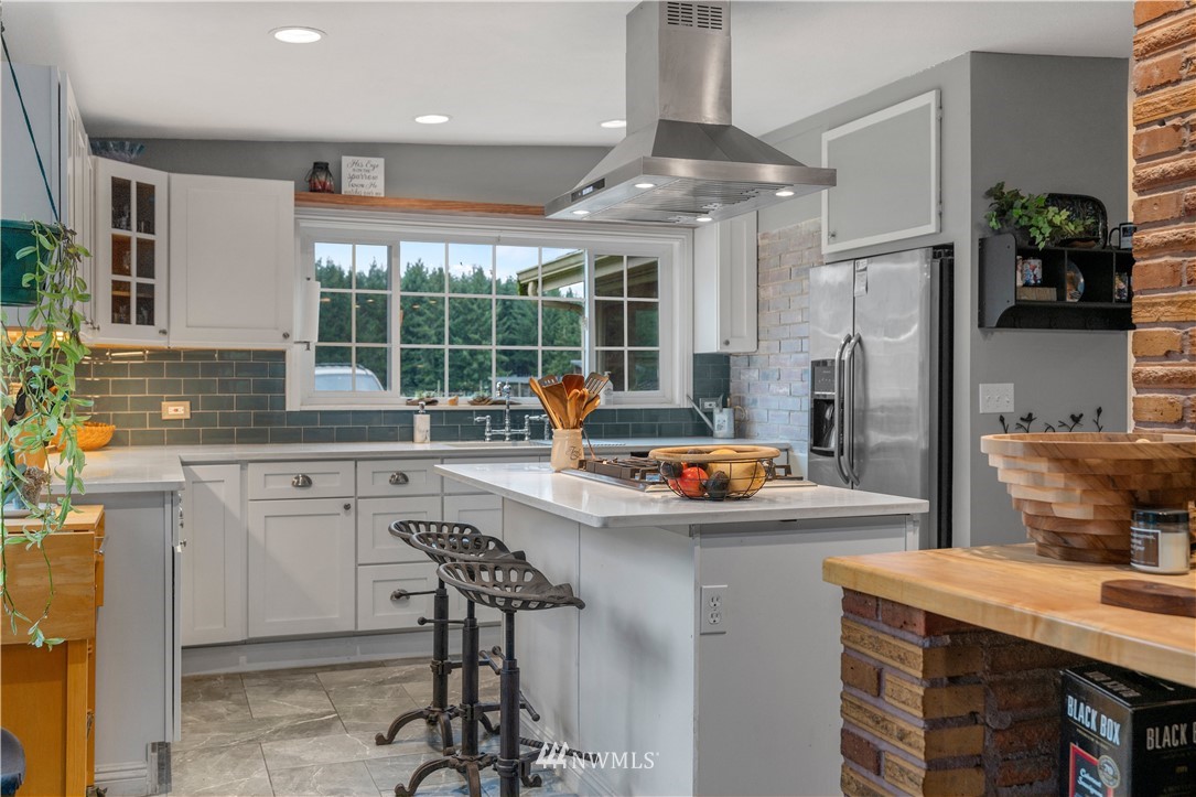 7232 191st Avenue Southwest Rochester, WA 98579 - Photo 13 of 40 a kitchen with stainless steel appliances granite countertop a sink a stove a refrigerator and white cabinets with wooden floor