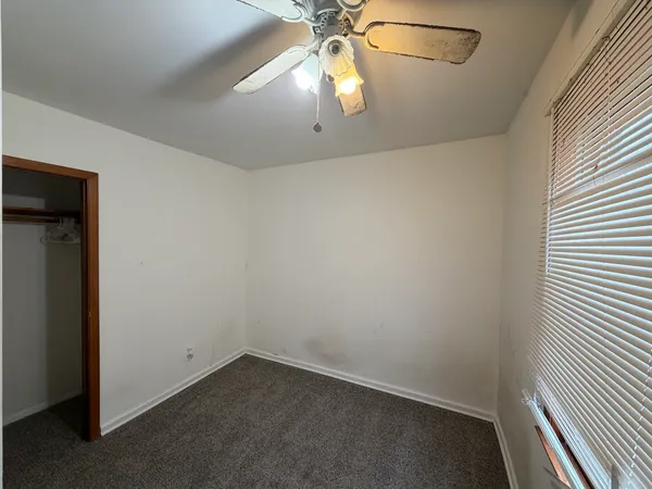 an empty room with a chandelier fan and windows